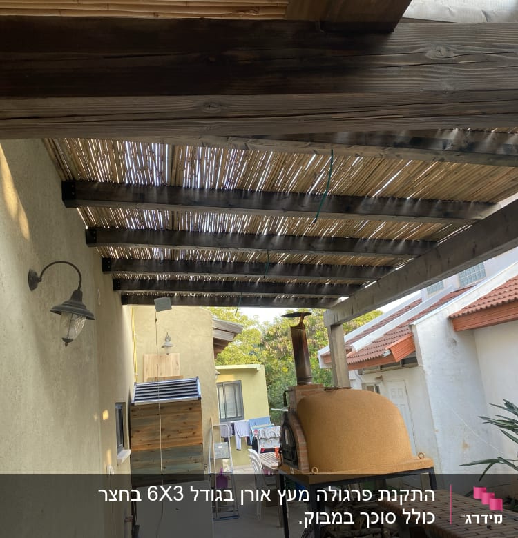 פרגולה מעץ עם גג קנים מעל תנור חיצוני